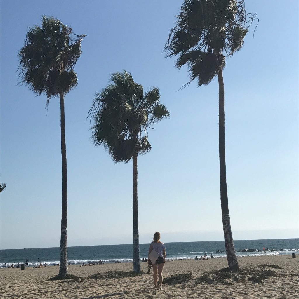 Nathalie at the beach, surrounded by palm trees.