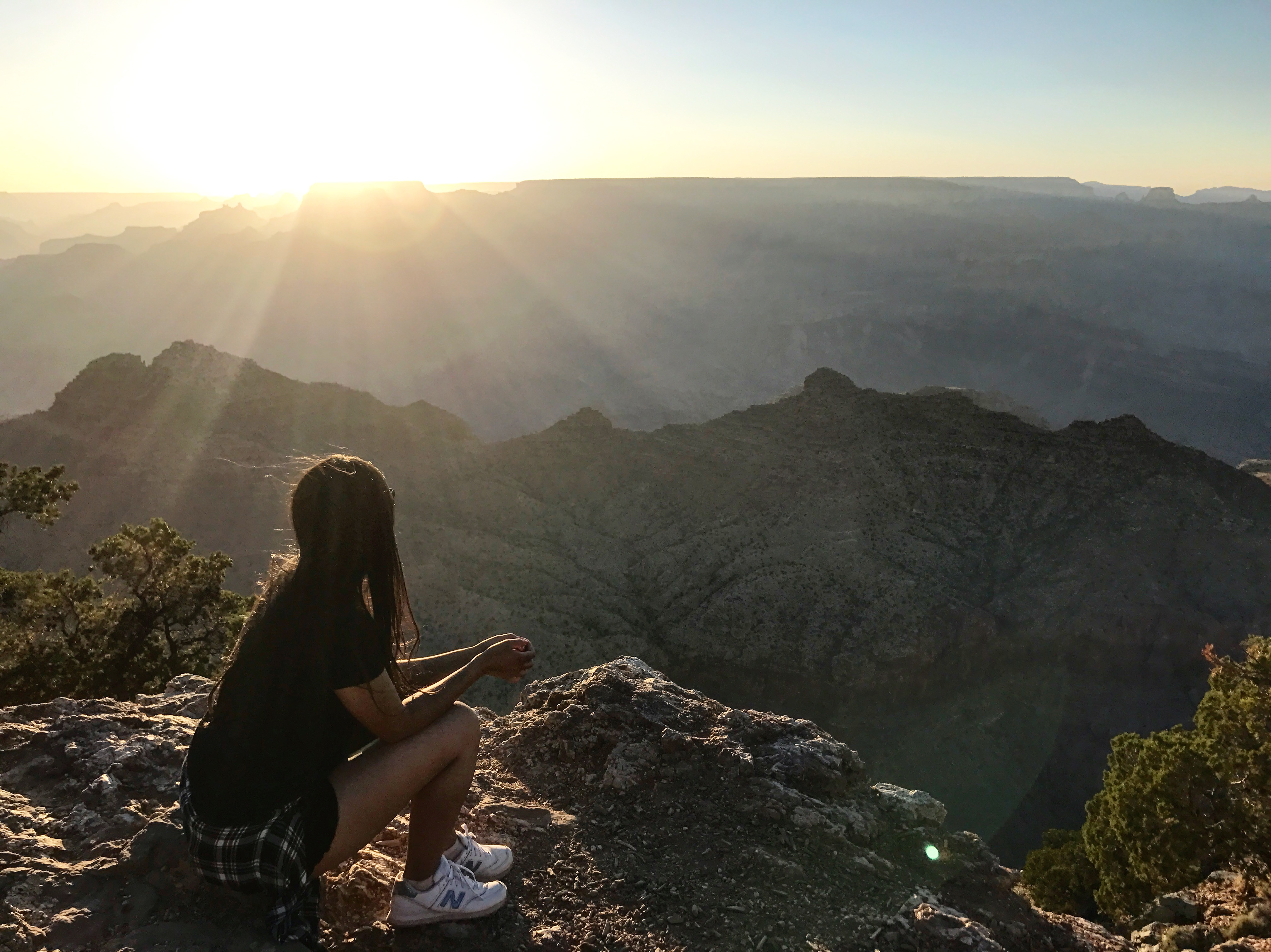 Mariana overlooking a beautiful sunrise at the edge of a mountain trail