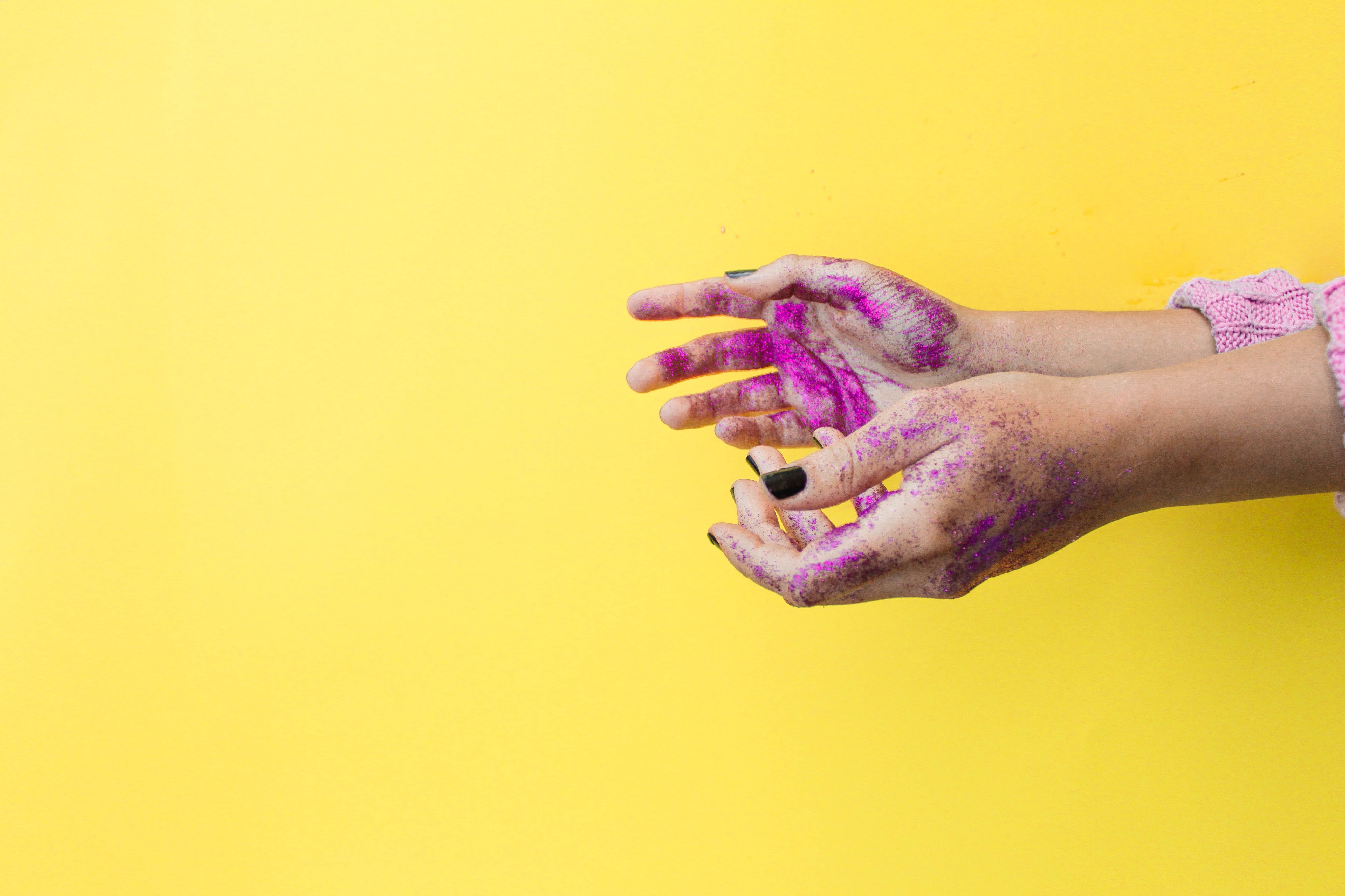 Paint-covered hands in front on a yellow background.